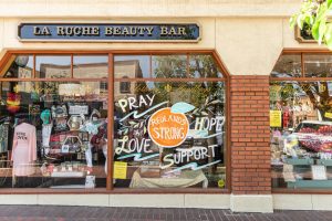 Photo of a storefront on State Street with "Redlands Strong" written on a painted navel orange on the store window.